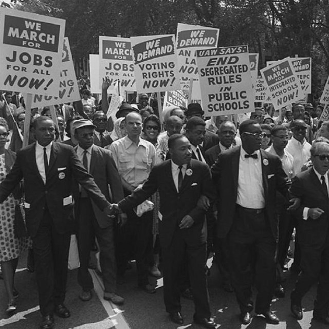 Photo of people marching in protest with signs. 